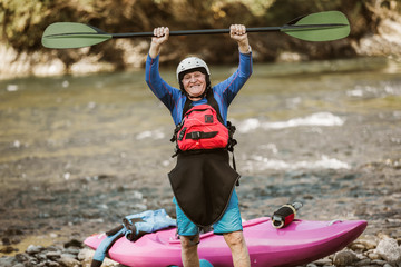 Senior man preparing for kayak tour on a mountain river.