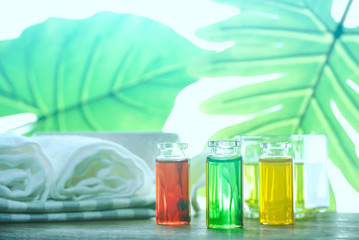 Aroma oil and liquid soap in the bottles with spa set on the table with background green leaf near the window , self care concept.