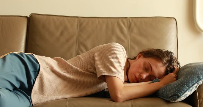 Exhausted young sleepy woman falls down on sofa. Apathetic tired lazy lady sleeping on couch at home alone. Funny girl lying asleep feeling lack of motivation, fatigue or depression concept