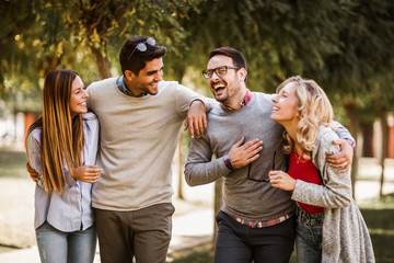 Group of young people walking through park. Friends having fun outdoor