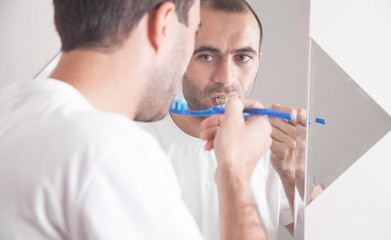 Caucasian man holding toothbrush in the bathroom.