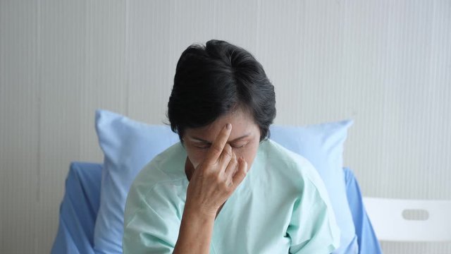 Hand held, close up portrait of senior Asian female patient having sinus headache, squeezing nosebridge, Negative human emotion facial expression feelings.