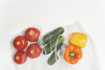 Reusable bags with, fresh vegetables tomatoes, cucumbers, bell peppers over white background