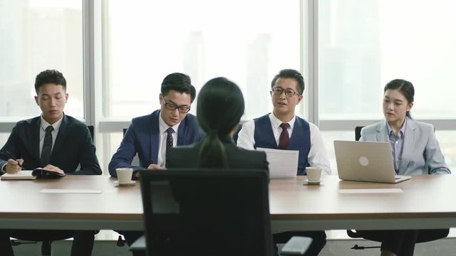 rear view of a young asian businesswoman being interviewed by a group of HR executives in conference room of modern corporation