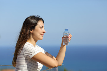 Woman holding a bottle of water in a hotel balcony