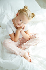 Little girl in bed with white linen. A child at home in the morning wakes up in his room. High quality photo.
