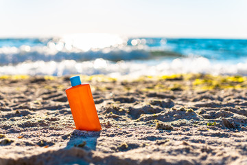 Bottle of sun protection and white cream bottle on the sand near the sea. Sun protection and skin pigmentation
