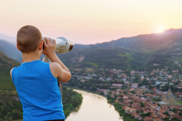 Boy in a blue t-shirt looking through the public coin operated binocular