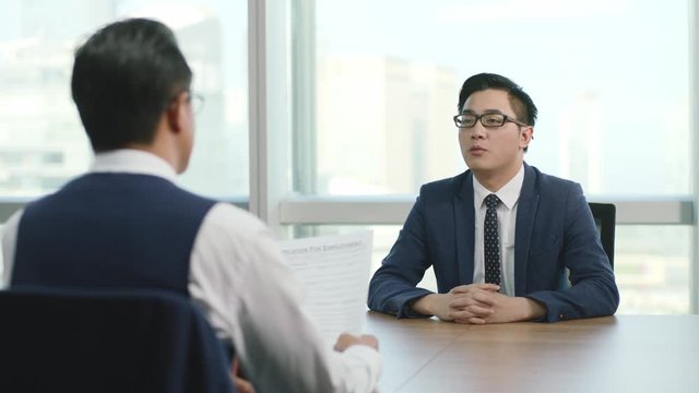 young asian business man being interviewed by HR manager in office of modern corporation, zooming in