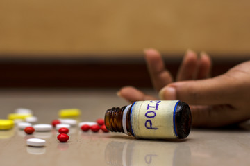 Bottle of poison pills in a female's hand committing suicide by overdosing of medication.