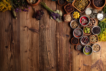 Natural medicine background. Assorted dry herbs in bowls and brass mortar on rustic wooden table.