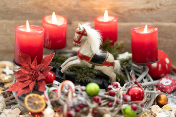 Rustikaler Adventskranz mit einem Holzschaukelpferd.