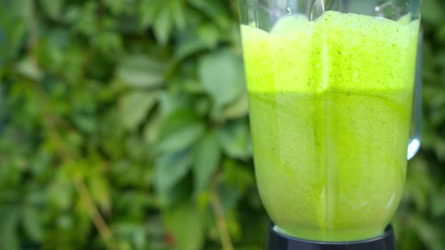 Working blander in the garden, making spinach banana detox smoothie