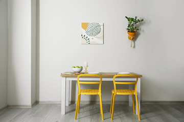 Table and chairs near light wall