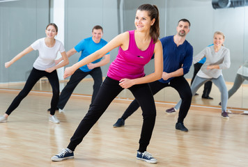 Fototapeta na wymiar Portrait of dancing girl practicing vigorous swing during group training in dance studio
