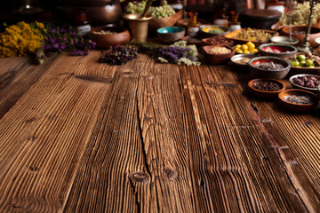 Natural medicine background. Assorted dry herbs in bowls and brass mortar on rustic wooden table.