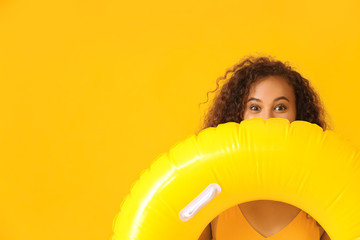 Beautiful young African-American woman with inflatable ring on color background