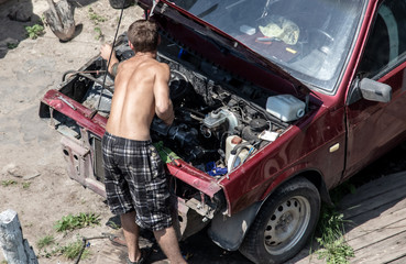 A man is repairing a motor in a car.