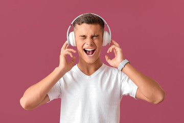 Emotional teenage boy listening to music on color background