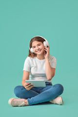 Teenage girl listening to music on color background