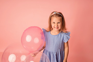 Obraz na płótnie Canvas Happy baby girl on a pink background with balloons. Celebration. Birthday