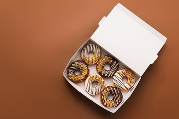 Box with tasty donuts on color background
