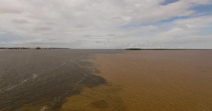 flying over of the meeting of the waters of the Amazon River and the Tapajos River. The waters of the Amazon River are brown in color and the Tapajos River is black.