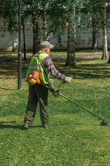 a man mows the grass on the lawn with a trimmer