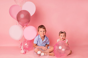 Happy child girl and boy on a pink background with balloons. Celebration. birthday
