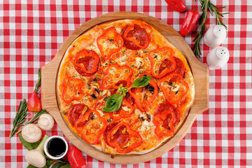 Neapolitan Pepperoni pizza with sausage, salami, pepper, cheese, vegetable, pepperoni spices and fresh basil and tomatoes sauce, served on a wooden board for a dinner in italian restaurant background