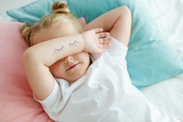 Little girl in bed with white linen. A child at home in the morning wakes up in his room. High quality photo.