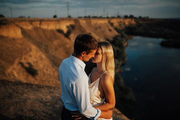 Fototapeta premium Man embracing and going to kiss sensual woman in their wedding day. Couple in love embracing in nature. Romantic young man and woman on walk in wedding day.