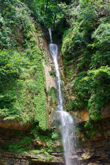 High waterfall falling from a cliff in beautiful southern forest.