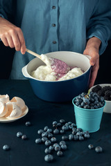 Woman mixing berries and cottage cheese. Cottage cheese casserole making.