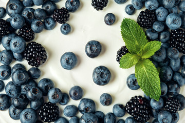 Close-up blueberry, blackberry and mint leaves on sour cream. Flat lay.