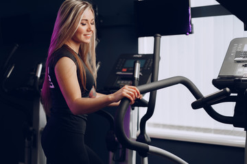 Fototapeta na wymiar Attractive young blonde woman exercising on cardio training apparatus