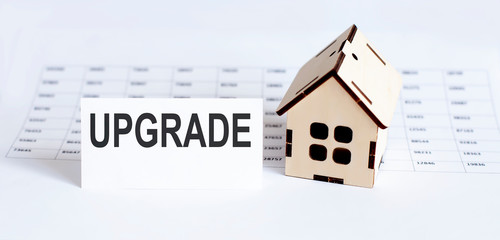 Closeup of house wooden model with blank for text UPGRADE on the chart background.