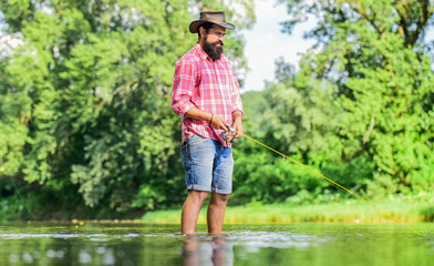 Fototapeta na wymiar Some kind meditation. Fish normally caught in wild. Trout farm. Fisherman alone stand in river water. Man bearded fisherman. Fisherman fishing equipment. Hobby sport activity. Calm and peaceful mood