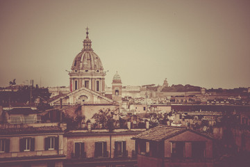 Fototapeta na wymiar Rome skyline with old colorful houses and rooftop terraces on sunny day. Dome of San Carlo al Corso basilica on the background. Rome, Italy