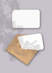 An envelope with two sheets of textured white paper on the grey background of the table. Mockup...