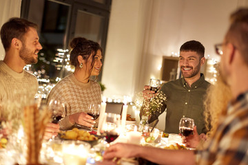 holidays, celebration and people concept - happy friends having christmas dinner at home drinking non-alcoholic red wine