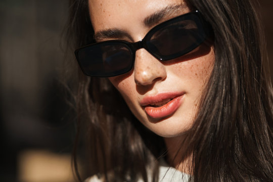 Serious young woman posing outdoors wearing sunglasses