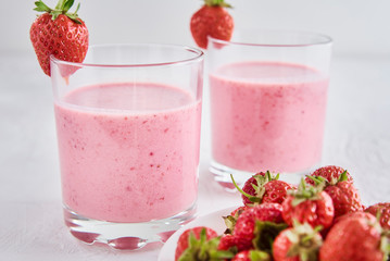 Two glasses with strawberry shake on white background