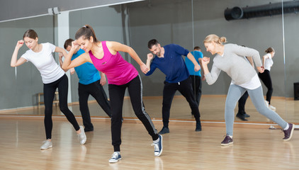 Fototapeta na wymiar Cheerful people practicing vigorous lindy hop movements in dance class.