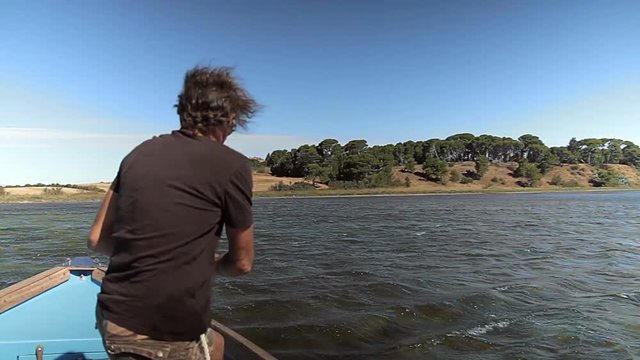 Un homme remonte l'encre de sa barque sur la lagune de Thau.
