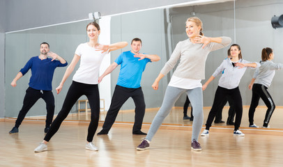 Fototapeta premium Sporty females and males doing stretching workout during group training at dance class