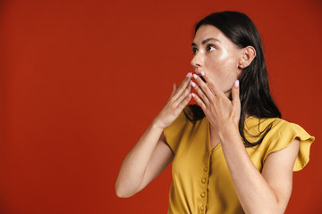 Image of young shocked woman expressing surprise and covering her mouth