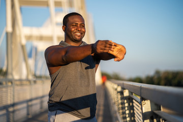 Young african-american man is exercising  on the bridge in the city.