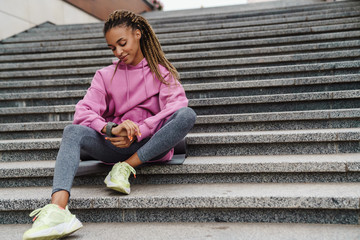 Young smilling fit woman checking smart watch