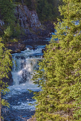 Plain waterfall Kivach.Long multistage flat waterfall. Seething waves and water falling on stones are visible. The slopes are rocky, spray and rainbow are visible. Russia, Karelia, Kivach